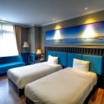 Luxurious hotel room features twin beds, modern decor, and ambient lighting.