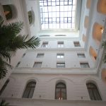 Capture of a sophisticated indoor atrium featuring a glass skylight and lush palm trees for a serene setting.