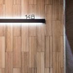 Contemporary wooden door with illuminated room number 148 in a hotel interior.